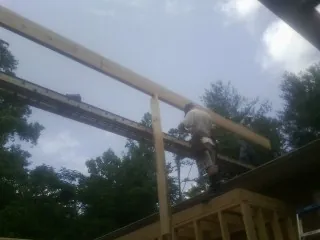 Carpenter setting a ridge beam over a new addition frame — Ice Dam Removal by Roofing Brothers in Artois