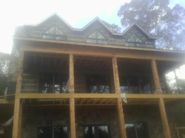 Dormers and porch framing on a large log home under construction — Roof Coating work by our crew in Artois