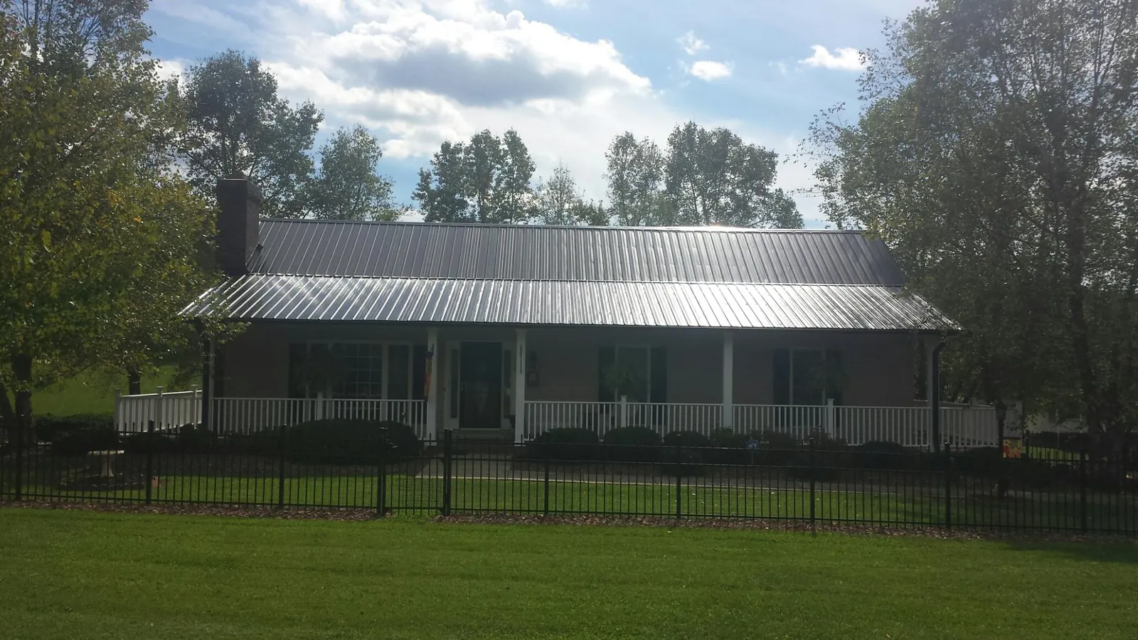 Gray metal roof on a brick ranch with a full width front porch — Gutter Guard Installation work by our crew in Artois