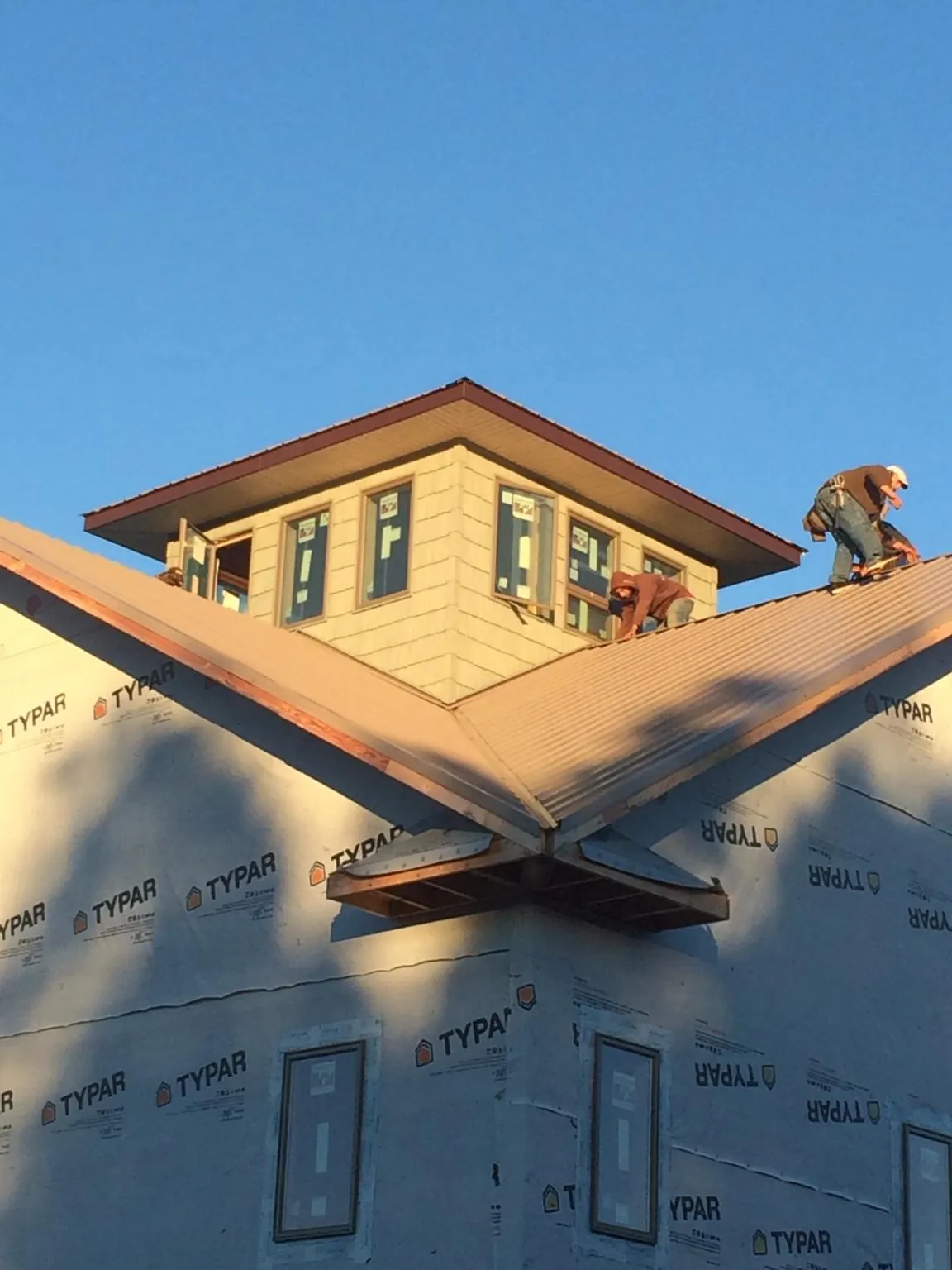 Roofers working around a rooftop cupola on a new metal roof at sunset — Roof Waterproofing in Artois by Roofing Brothers